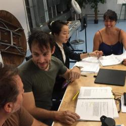 The cast of Monster in the Hall sit at a table read